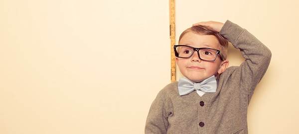 Child standing against a wall being measured.